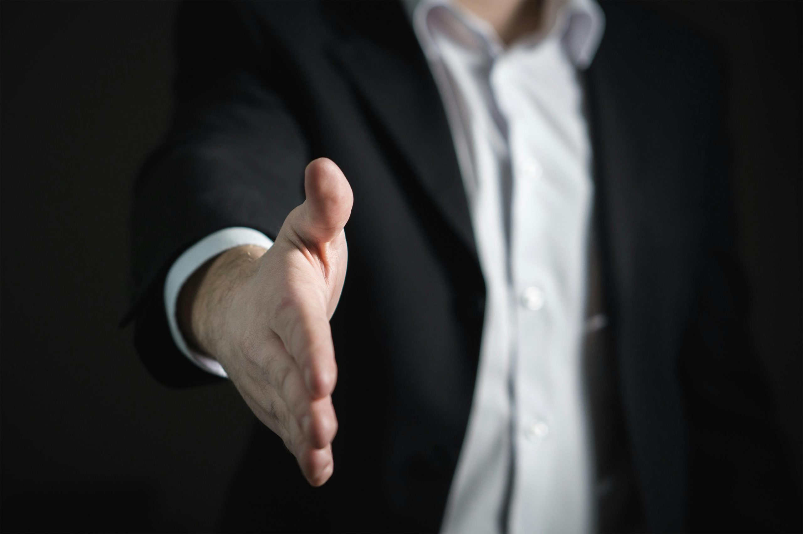 Accrédité Close-up of a businessman extending hand for a handshake, symbolizing agreement and partnership.